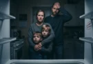 A family looking at an empty refrigerator with a SNAP EBT card in the foreground, highlighting the crisis during the US government shutdown.